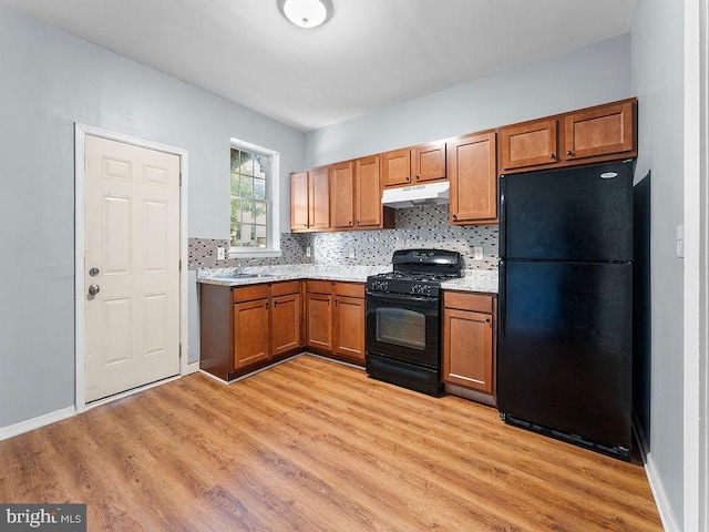 kitchen with backsplash, sink, black appliances, and light wood-type flooring