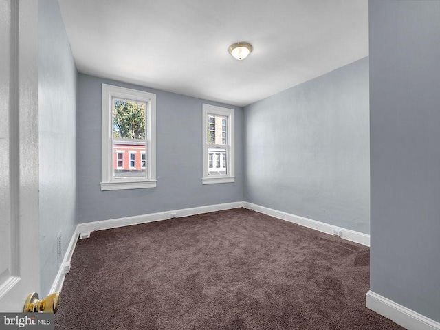 unfurnished room featuring dark carpet