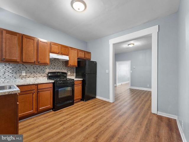 kitchen featuring backsplash, black appliances, and light hardwood / wood-style floors