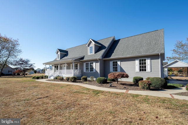 cape cod-style house featuring covered porch and a front lawn