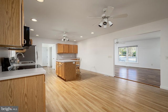 kitchen featuring a kitchen island, sink, stainless steel refrigerator, and light hardwood / wood-style floors