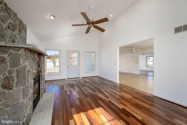 unfurnished living room featuring dark hardwood / wood-style flooring, high vaulted ceiling, ceiling fan, and a fireplace