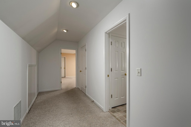 corridor with vaulted ceiling and light carpet