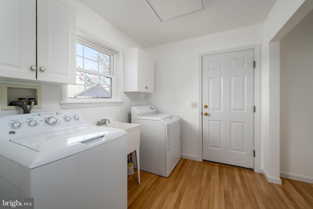 washroom with light hardwood / wood-style flooring, washing machine and dryer, cabinets, and sink