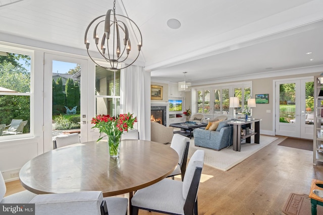 155 E Oakland Ave, Doylestown, PA 18901 - dining area featuring french doors, light wood-type flooring, a chandelier, a warm lit fireplace, and crown molding