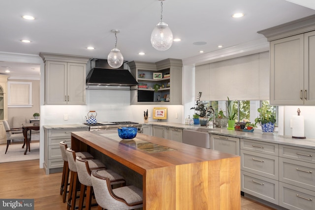 155 E Oakland Ave, Doylestown, PA 18901 - kitchen with wall chimney range hood, butcher block counters, a sink, ornamental molding, and a kitchen island