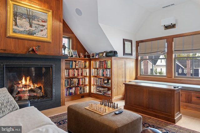 155 E Oakland Ave, Doylestown, PA 18901 - living area with vaulted ceiling, a lit fireplace, wood walls, and wood finished floors