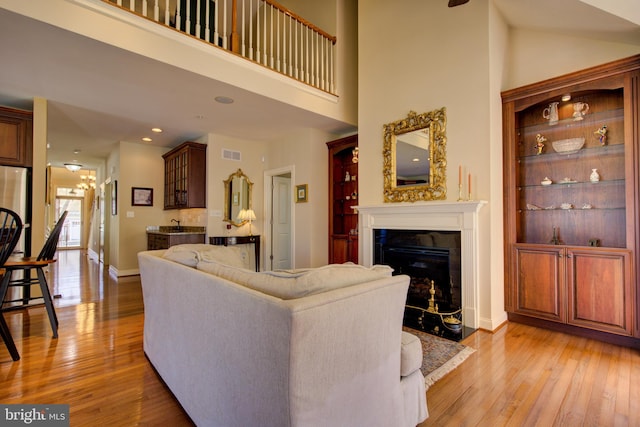 living room with a high ceiling, a fireplace, and light hardwood / wood-style flooring