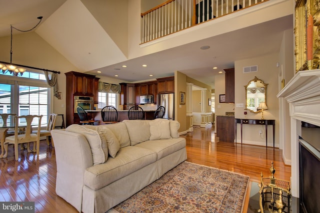 living room featuring light hardwood / wood-style floors, a chandelier, and high vaulted ceiling