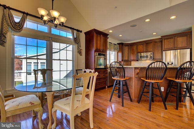 dining room with lofted ceiling, a healthy amount of sunlight, and light hardwood / wood-style flooring