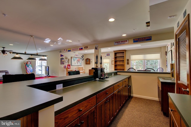 kitchen with kitchen peninsula, light carpet, and sink