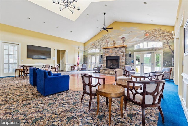 dining space featuring high vaulted ceiling, a fireplace, ceiling fan with notable chandelier, and dark carpet