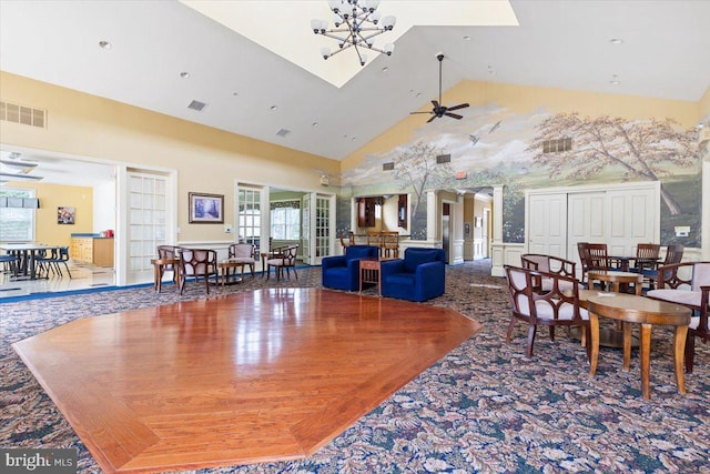 dining area featuring high vaulted ceiling and ceiling fan with notable chandelier