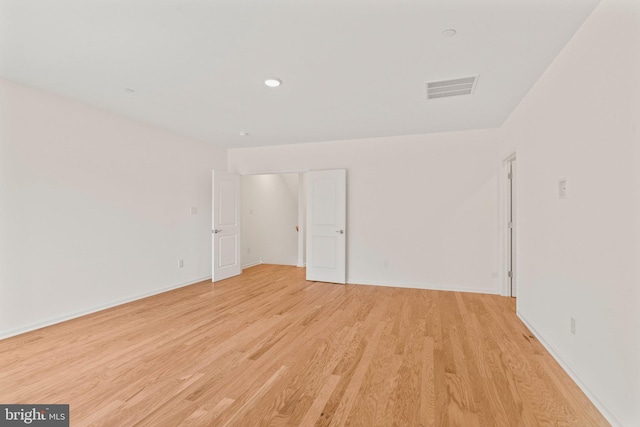 empty room with light wood finished floors, visible vents, baseboards, and recessed lighting