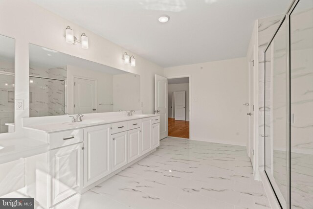 bathroom featuring a marble finish shower, marble finish floor, double vanity, and a sink