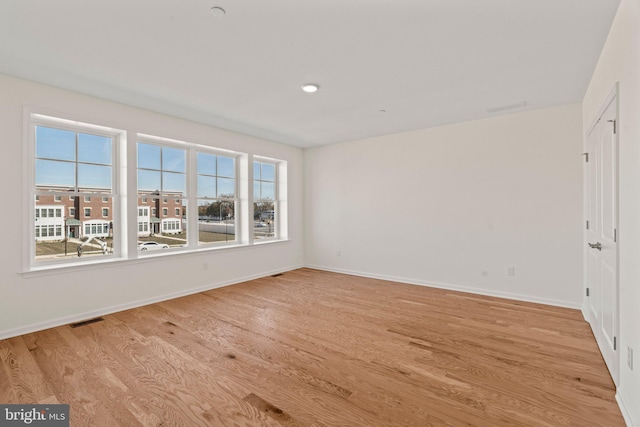 unfurnished room featuring baseboards, light wood-style floors, and visible vents