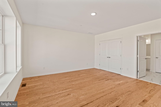 unfurnished bedroom featuring visible vents, wood finished floors, and baseboards