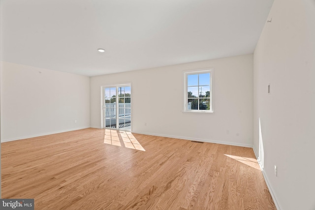 spare room with visible vents, light wood-style flooring, and baseboards