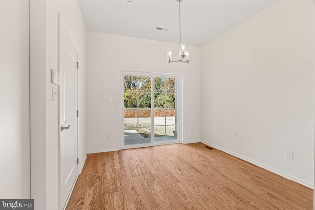 unfurnished dining area with baseboards, an inviting chandelier, visible vents, and wood finished floors