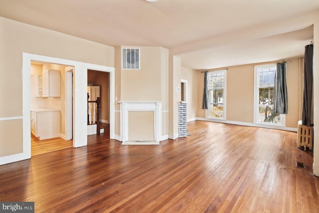 unfurnished living room featuring hardwood / wood-style flooring and radiator heating unit