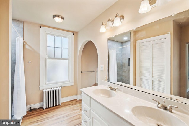 bathroom with vanity, hardwood / wood-style flooring, a shower with shower curtain, and radiator