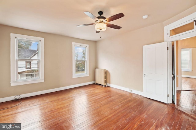 empty room with radiator heating unit, ceiling fan, and light hardwood / wood-style flooring