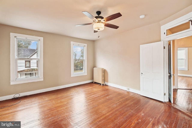 205 Walnut St, Pocomoke City, MD 21851 - empty room featuring radiator heating unit, hardwood / wood-style floors, healthy amount of natural light, and a ceiling fan