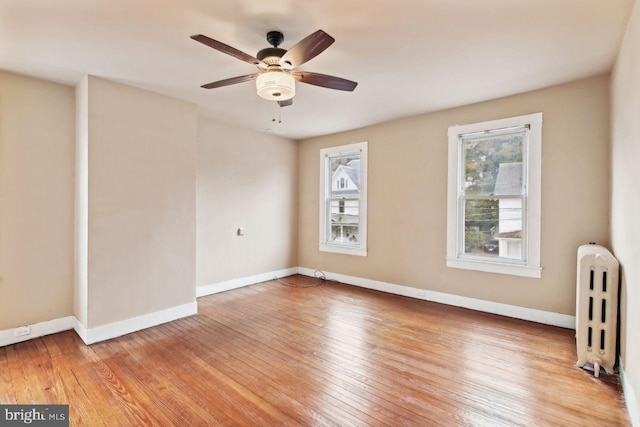 spare room featuring radiator heating unit, ceiling fan, and light hardwood / wood-style flooring