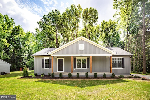 view of front of home featuring covered porch, central AC, roof with shingles, and a front yard