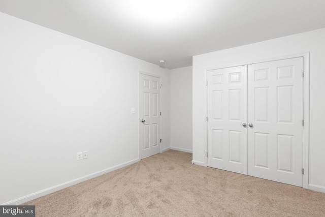 unfurnished bedroom with a closet and light carpet