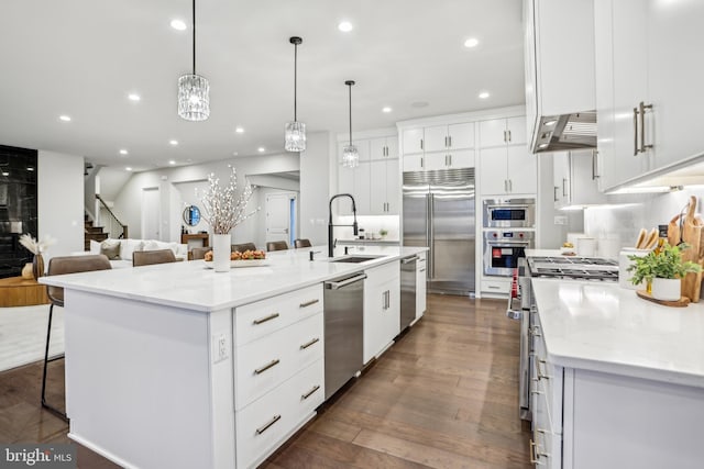 kitchen with a large island, sink, white cabinets, and high end appliances