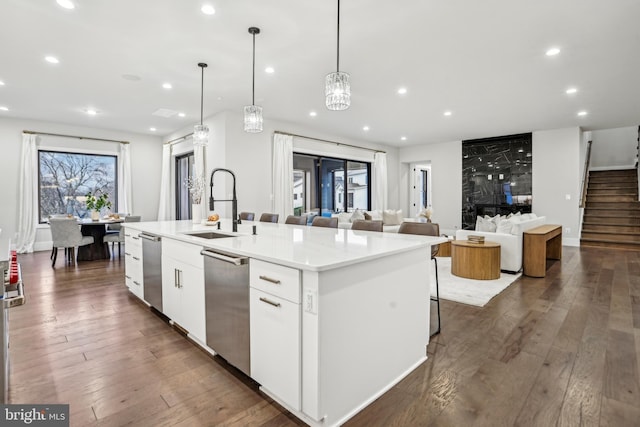 kitchen featuring pendant lighting, a center island with sink, sink, dark hardwood / wood-style floors, and white cabinetry