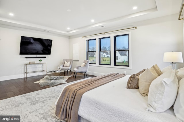 bedroom with a tray ceiling and hardwood / wood-style floors