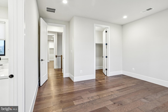 unfurnished bedroom with a spacious closet and dark wood-type flooring