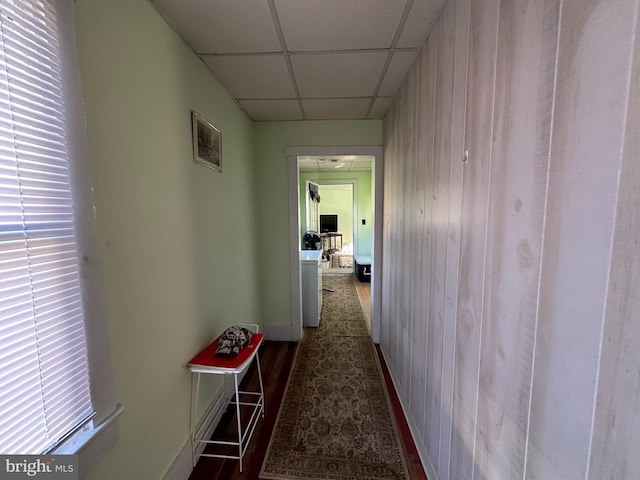 corridor featuring wood walls and a drop ceiling