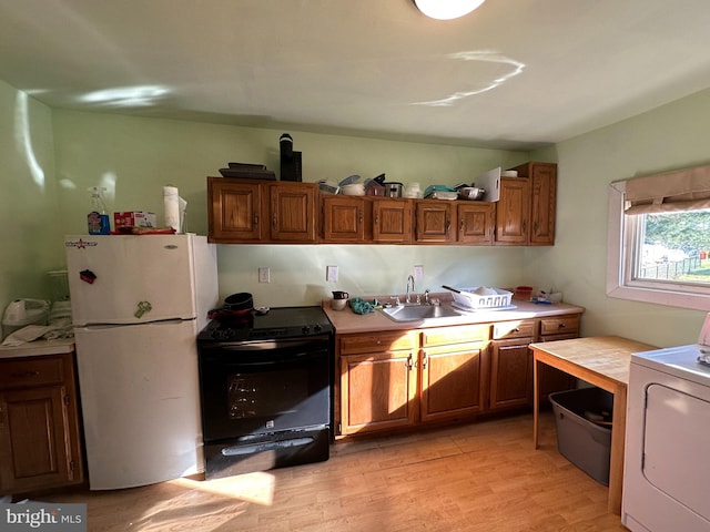 kitchen with sink, washer / clothes dryer, light hardwood / wood-style flooring, black / electric stove, and white fridge