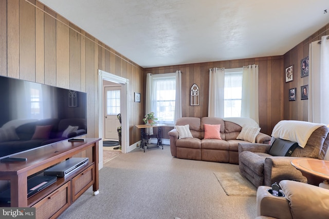 carpeted living room featuring wood walls