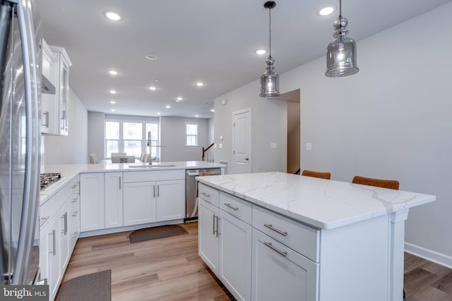 kitchen featuring stainless steel appliances, white cabinets, sink, and a kitchen island