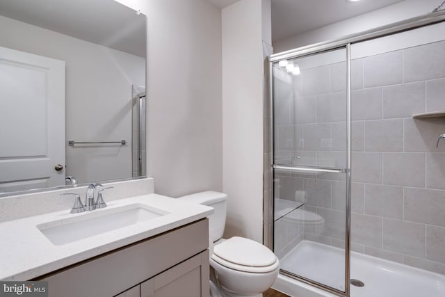 bathroom with toilet, vanity, and a shower with door