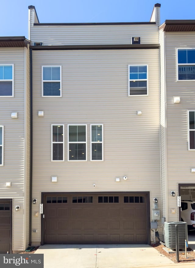 rear view of house with central AC and a garage