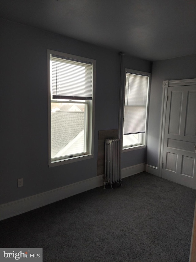 carpeted empty room featuring radiator heating unit