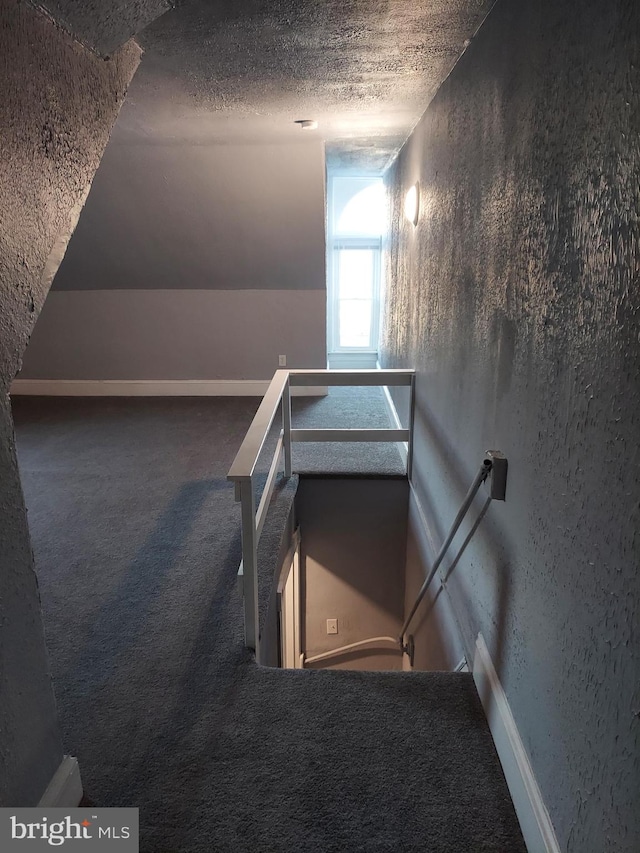 stairs with carpet floors and a textured ceiling