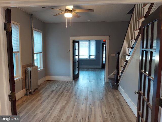 foyer entrance featuring ceiling fan, radiator, french doors, and light hardwood / wood-style floors