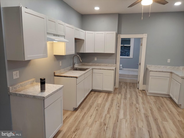 kitchen with white cabinets, light hardwood / wood-style floors, ceiling fan, and sink