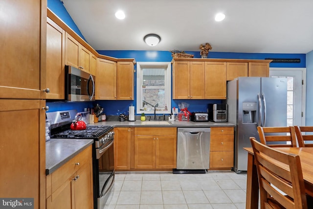 kitchen with sink, light tile patterned floors, stainless steel appliances, and vaulted ceiling