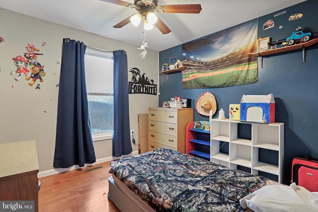 bedroom featuring a ceiling fan, wood finished floors, visible vents, and baseboards