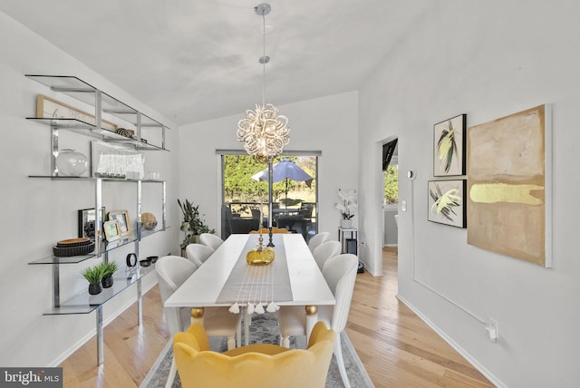 dining room with lofted ceiling, light wood-type flooring, and an inviting chandelier