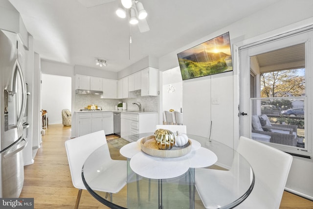 dining room with ceiling fan, sink, and light wood-type flooring