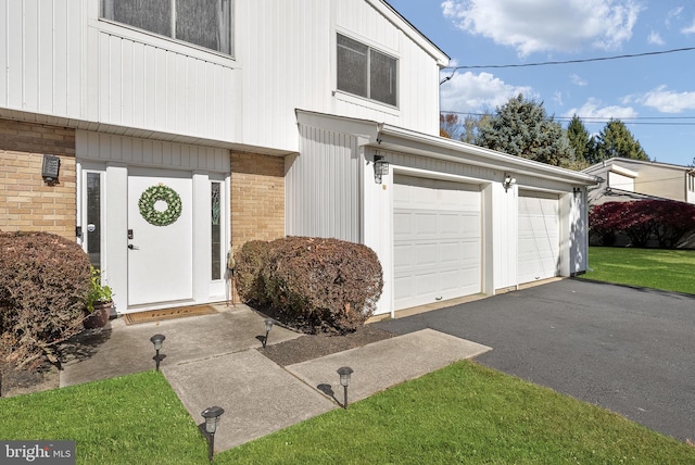 view of exterior entry featuring a yard and a garage