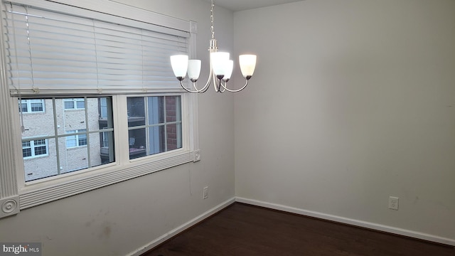 spare room with dark hardwood / wood-style floors and a chandelier